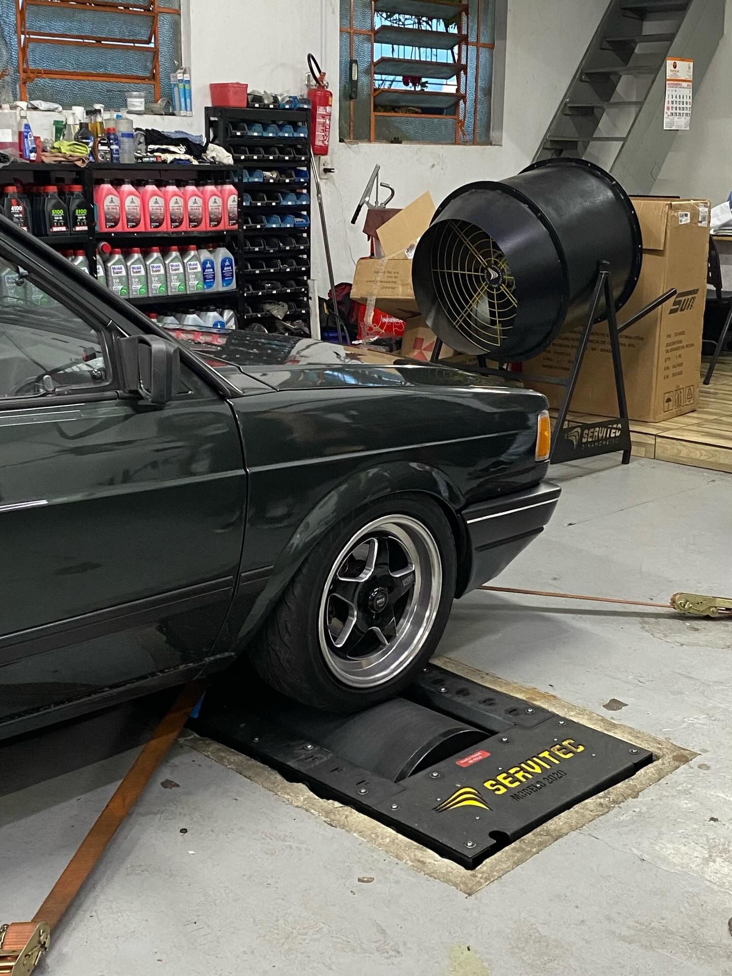 VW Gol verde escuro sobre o dinamômetro Servitec na oficina