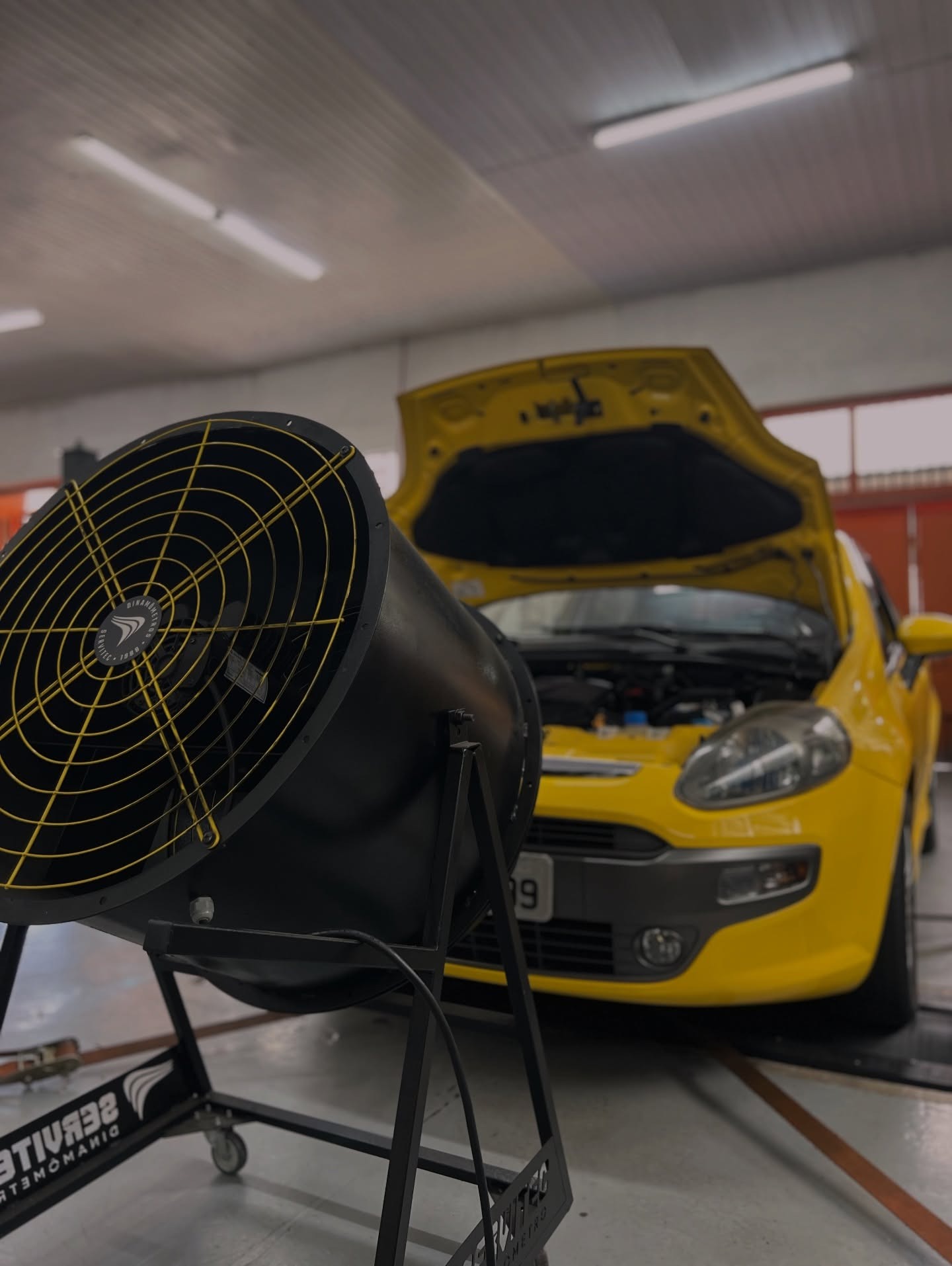 Ventilador e Fiat Punto amarelo durante teste em dinamômetro